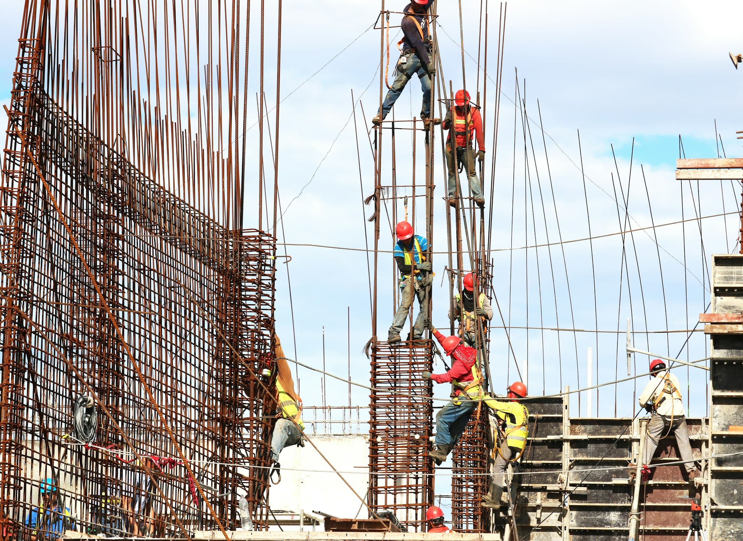 Workers in hard hats fixing reinforcement bars on a concrete column
