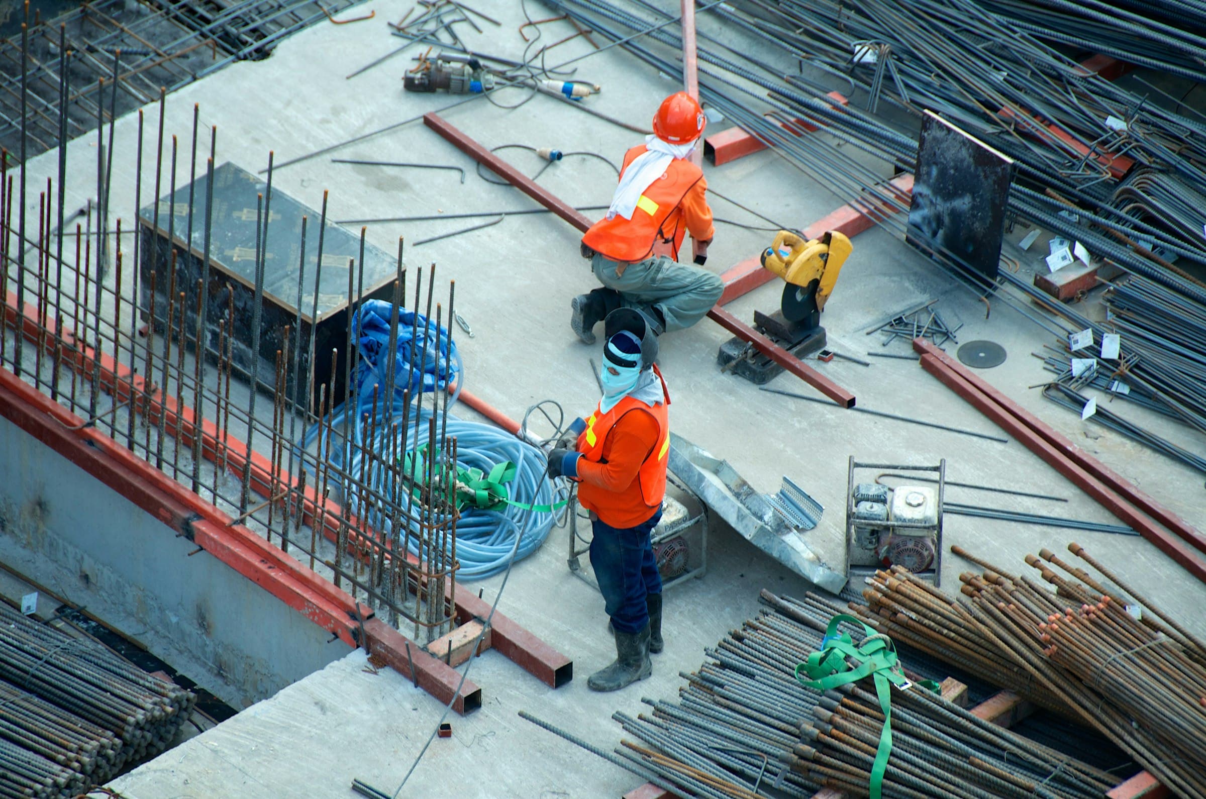 Aerial view of site workers laying out reinforcement and conduit on a concrete deck